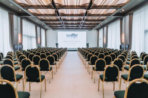 an empty room with chairs and a projection screen at Royal Garden Assago Milano in Assago