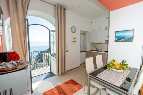 cocina y comedor con mesa y balcón en Il Paradiso sul Mare Apartment en Scala