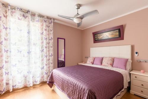 um quarto com uma cama roxa e uma ventoinha de tecto em Martiánez Playa: Coastal Location em Puerto de la Cruz
