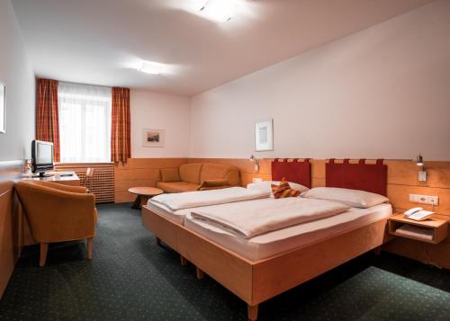a hotel room with a bed and a couch at Hotel Figl ***S in Bolzano