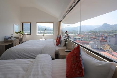 a bedroom with two beds and a large window at Cong Fu Hotel in Bắc Hà