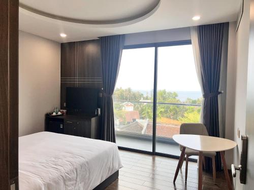 1 dormitorio con cama, mesa y ventana grande en Le Anh Hotel, en Phu Quoc