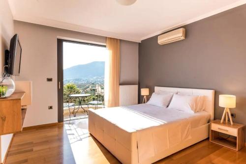 una camera con letto bianco e balcone di Lavish Athens Pool Villa - Indulge in Luxury ad Anávissos
