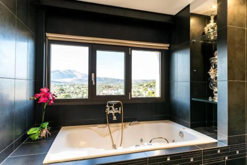 a bath tub in a bathroom with a window at Lavish Athens Pool Villa - Indulge in Luxury in Anavyssos
