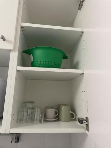 - un placard avec un bol vert et des tasses dans l'établissement Logement de charme à cachan, à Cachan