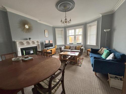 uma sala de estar com uma mesa e um sofá azul em Silverdale Apartments em Eastbourne