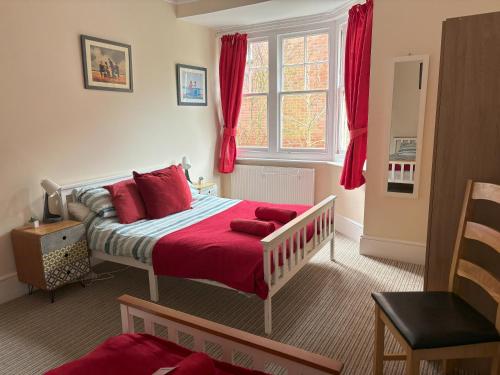 a bedroom with a bed with red sheets and a window at Silverdale Apartments in Eastbourne