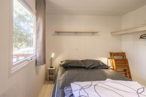 a small bedroom with a bed and a window at Mobil home La Palmyre in Les Mathes