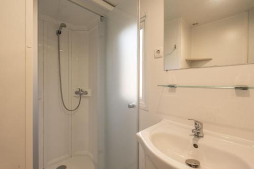 a white bathroom with a shower and a sink at Mobil home La Palmyre in Les Mathes