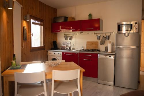 uma cozinha com armários vermelhos e uma mesa de madeira em Chalet dans plusieurs hectares de nature em Barjols