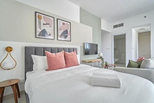 a bedroom with a large white bed with pink pillows at Stella Stays Elegant Studio Dubai JVC Large Terrace in Dubai