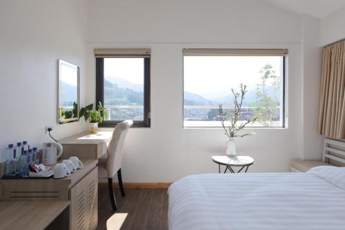 a bedroom with a bed and a desk and two windows at Cong Fu Hotel in Bắc Hà