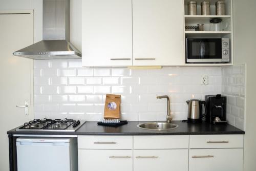 a white kitchen with a sink and a stove at De Berkenhof in Nes
