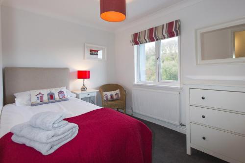 Penbryn的住宿－Y Llofft Tresaith，一间卧室配有一张带红色毯子的床和窗户。
