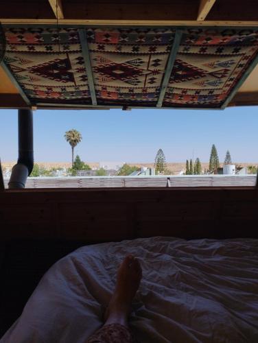a persons leg laying on a bed looking out a window at Star Gazing in Mitzpe Ramon