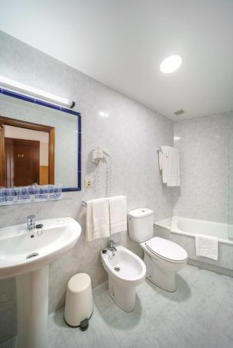 a bathroom with a sink and a toilet and a tub at Hotel El Puente in Sanxenxo