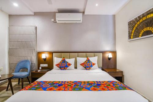 a bedroom with a bed and a blue chair at FabHotel Prime D Dev in Vijayawāda