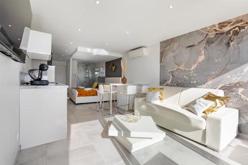 Il comprend un salon avec un mobilier blanc et une cuisine. dans l'établissement Village Naturiste R4N - Impérial Héliopolis Luxe, au Cap d'Agde