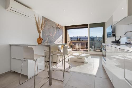 une cuisine blanche avec une table et des chaises dans l'établissement Village Naturiste R4N - Impérial Héliopolis Luxe, au Cap d'Agde