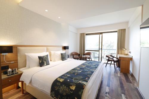 a hotel room with a large bed and a desk at INFINITEA CENTRIC DHARAMSHALA in Dharamshala