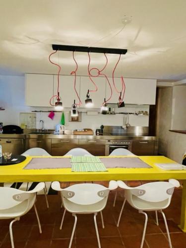 a kitchen with a yellow table and white chairs at Rustico Il Nove in Piazzogna