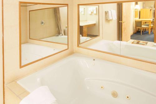 a bath tub in a bathroom with two mirrors at Days Inn by Wyndham Farmer City in Farmer City