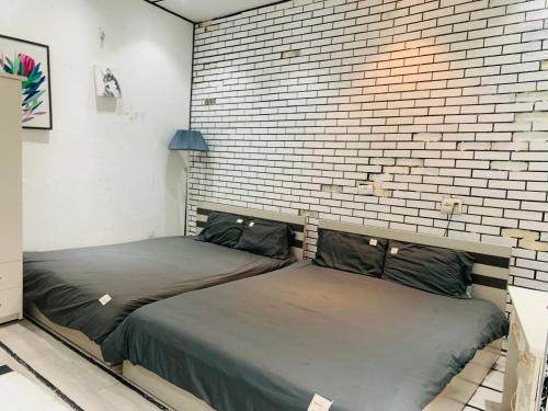 2 camas en una habitación con una pared de ladrillo en Heart of Quarter Twin room, Balcony, Projector en Hanói