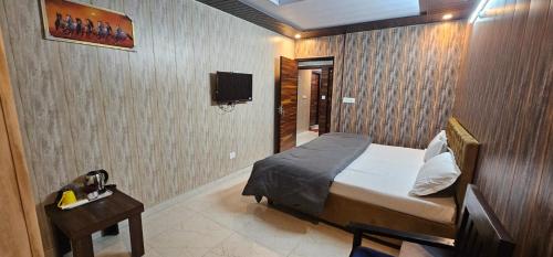 a bedroom with a bed and a tv on a wall at Hotel Mussoorie Gold Mary in Mussoorie