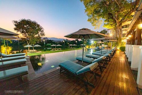 a row of lounge chairs next to a swimming pool at Buri Sriping Riverside Resort & Spa - SHA Extra Plus in Chiang Mai