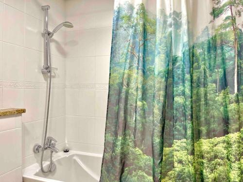 a bathroom with a shower curtain with a forest at Urban Oasis Duplex Loft Wabundant Natural Light in Dubai