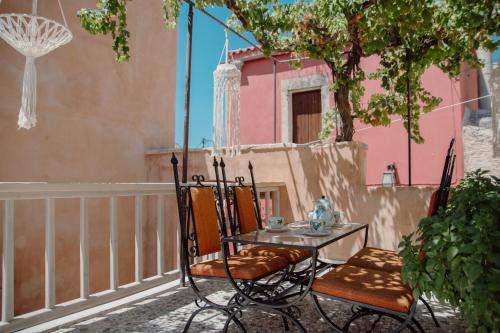 a table and chairs on a balcony with a pink house at CARPE DIEM HOTEL in Archanes