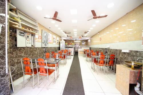 a dining hall with orange chairs and tables in a restaurant at Sri sai baba guest house in Puducherry