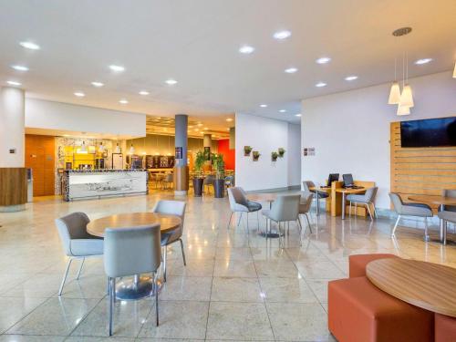 a lobby with tables and chairs in a building at ibis Vitoria Praia de Camburi in Vitória