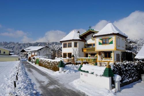 ein Haus ist mit Schnee bedeckt auf einer verschneiten Straße in der Unterkunft Ferienwohnung Dobner Schlössl in Angath