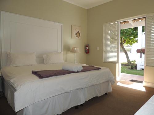 Un dormitorio con una gran cama blanca y una ventana en The Dunes Studio 20, en Plettenberg Bay