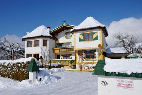 ein schneebedecktes Haus mit einem Schild davor in der Unterkunft Ferienwohnung Dobner Schlössl in Angath