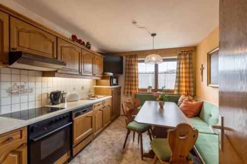 eine Küche mit Holzschränken und einem Tisch und Stühlen in der Unterkunft Ferienwohnung Dobner Schlössl in Angath