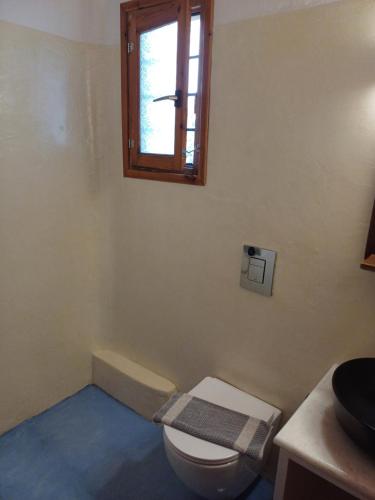 a bathroom with a toilet and a window at Siroco's Rooms And Studios in Parikia