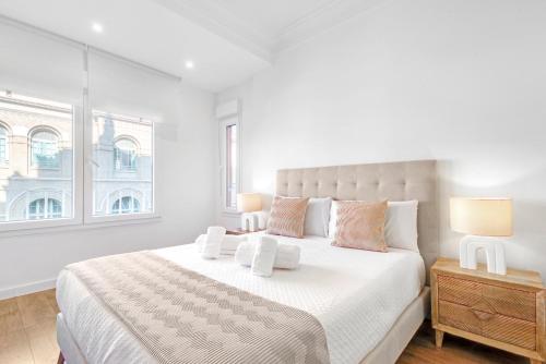 サラゴサにあるHogar Lujoso Centro Zaragozaの白いベッドルーム(ランプ2つ付きの大型ベッド1台付)