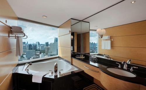 DoubleTree by Hilton Shanghai Pudong - Present welcome cookie في شانغهاي: حمام مع حوض استحمام ونافذة مطلة على المدينة