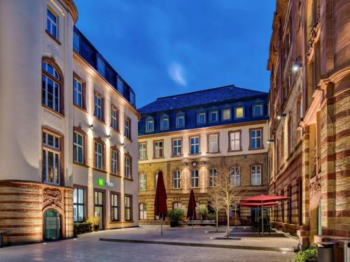 a group of buildings in a courtyard with umbrellas at Ibis Styles Trier City in Trier