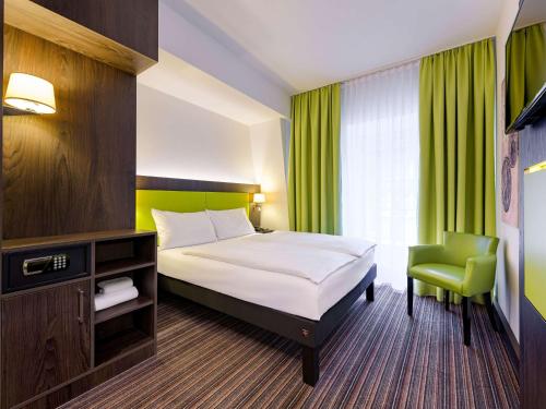 a hotel room with a bed and a chair at Ibis Styles Trier City in Trier