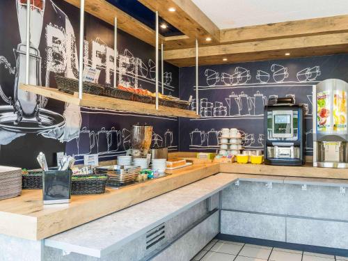 a restaurant with a counter with graffiti on the wall at ibis budget Senlis in Senlis