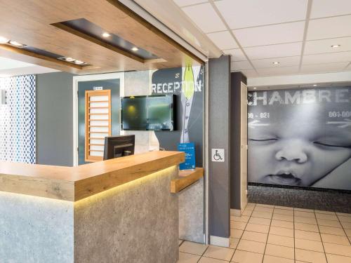 un espace d'attente dans un hôpital avec un visage de bébé sur le mur dans l'établissement ibis budget Senlis, à Senlis