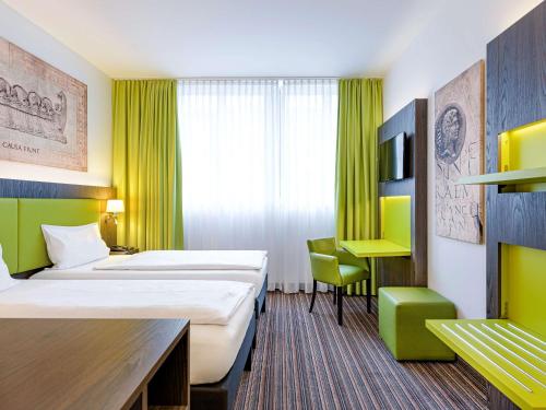 a hotel room with two beds and a desk at Ibis Styles Trier City in Trier