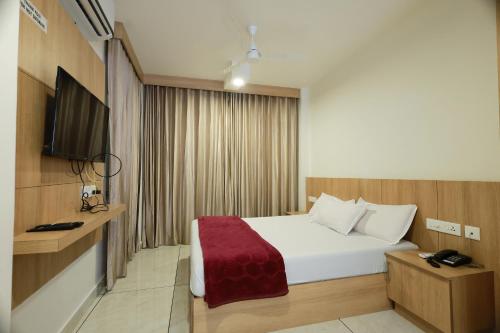 a hotel room with a bed and a flat screen tv at Slice of Heaven in Mundakāyam