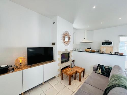 un salon avec un canapé et une télévision dans l'établissement Maison du centre, charme & océan, à Saint-Jean-de-Monts