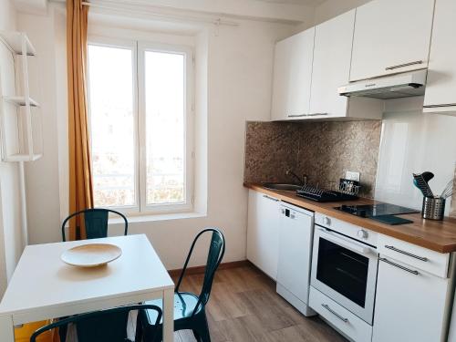 une cuisine avec des armoires blanches et une table avec des chaises dans l'établissement Deux pièces rénové climatisé cœur du vieil Antibes, à Antibes