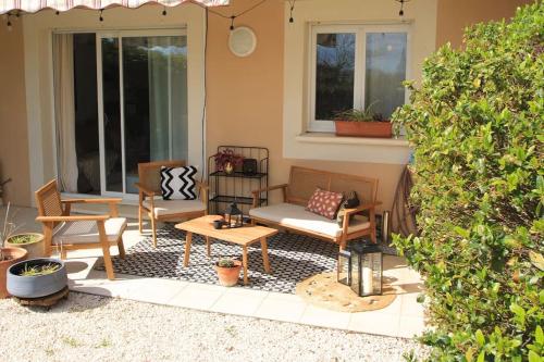 eine Terrasse mit Stühlen, einem Sofa und einem Tisch in der Unterkunft Cosy appartement entre vignes et garrigue avec piscine in Péret