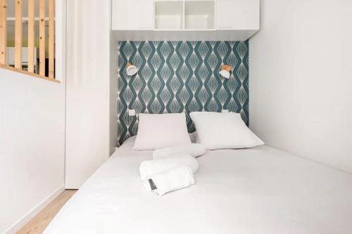 una piccola camera da letto con un letto bianco con due cuscini di L'Ecrin Vert - 150m Restaurant 3 étoiles a Vonnas